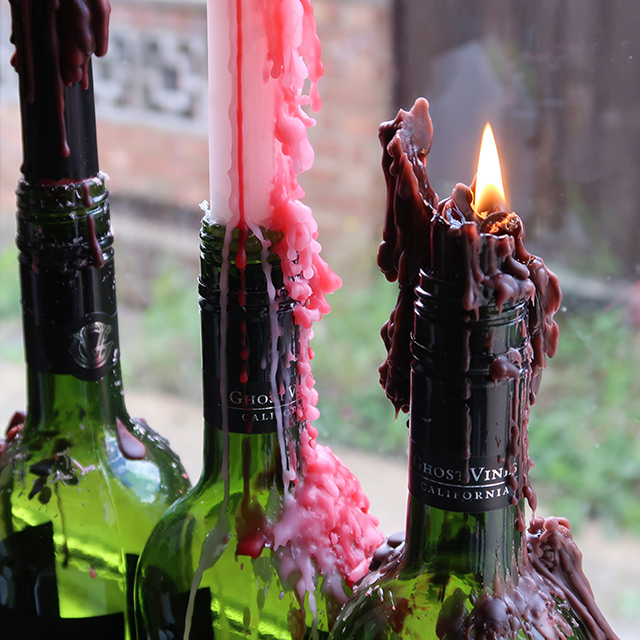 The three varieties of dripping taper candle in wine bottles, lit and quite melted