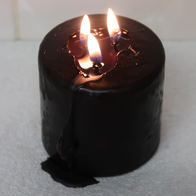 The pillar candle, lit and starting to melt